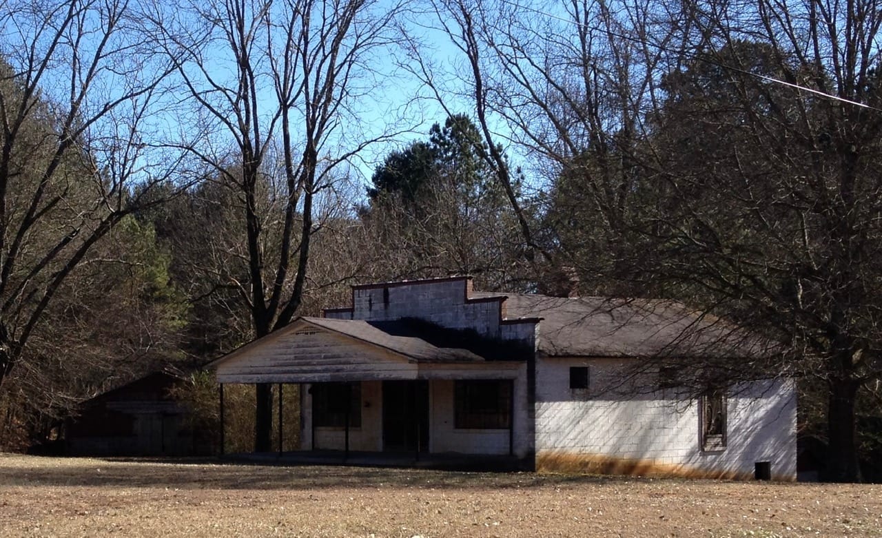 The J.B. Mathis General Store before restoration — abandoned, overgrown, with deteriorating roof