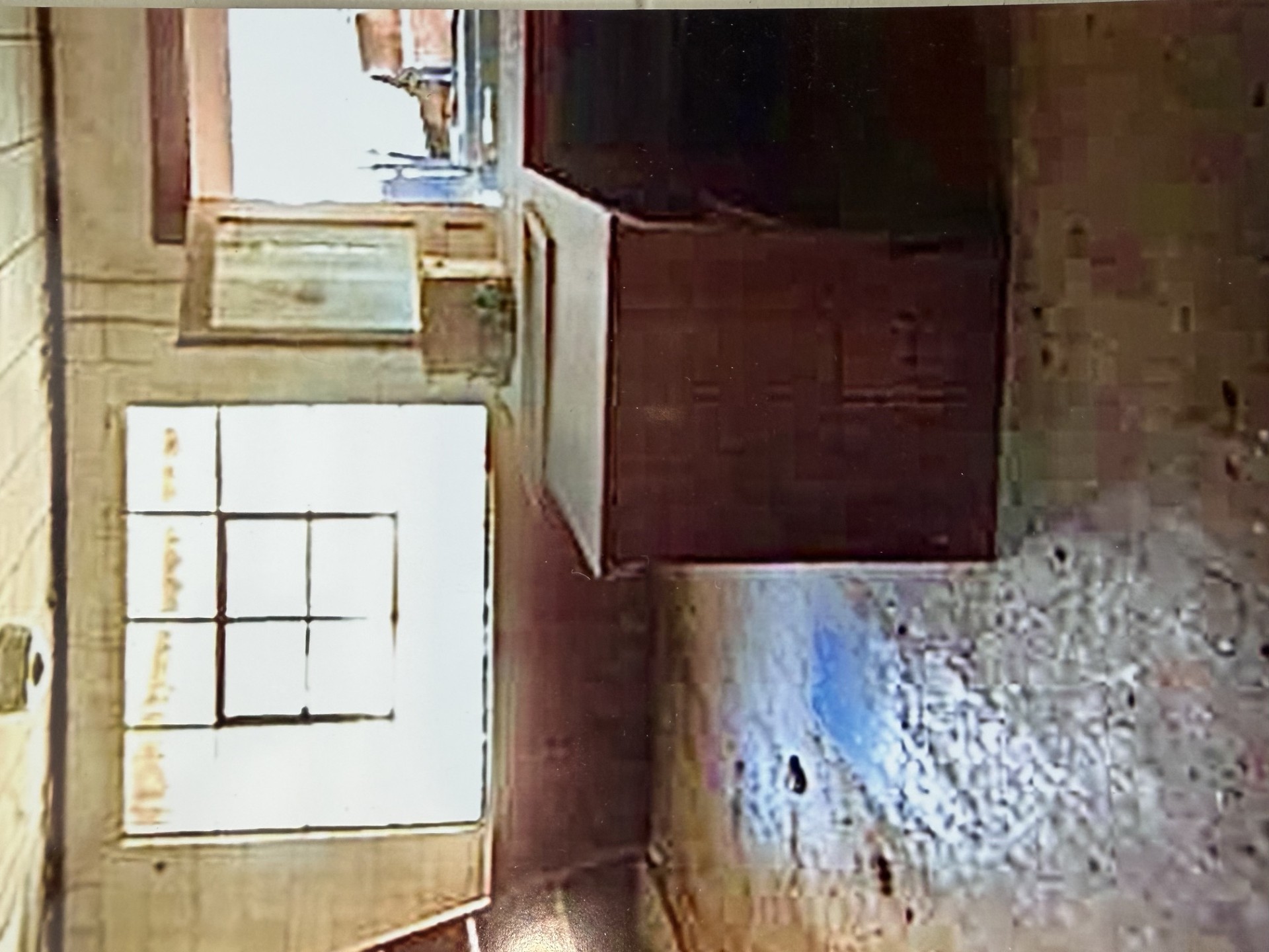 Interior view before restoration — original counter, window, and worn tile floor