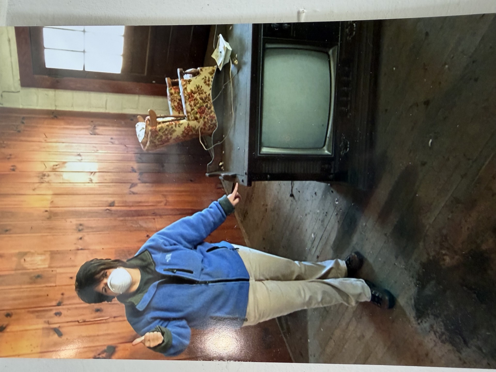 Lashelle Thompson gives a thumbs-up on day one of demolition — old TV and wood paneling behind her